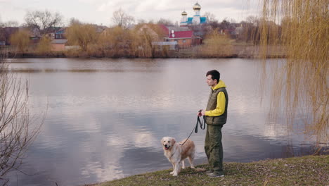 man walking his dog by the river in a village