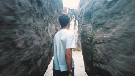 teenage boy walking in between narrow boulder cliff path in forest fontainebleau