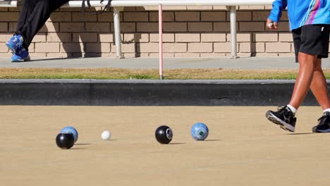 players engage in a lawn bowls game on a sunny day, showcasing precise movements and strategic gameplay
