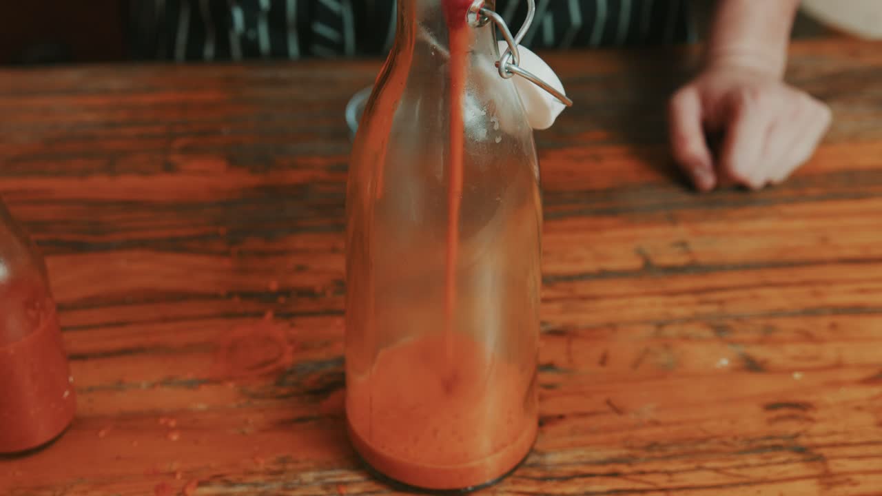 Versamento di salsa cremosa di peperoni rossi in una bottiglia di vetro per la conservazione