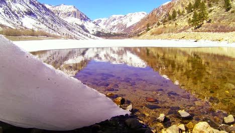 Die-Kamera-Fährt-Unter-Einem-Gletscher-Hervor,-Um-Einen-Bergsee-Zu-Enthüllen