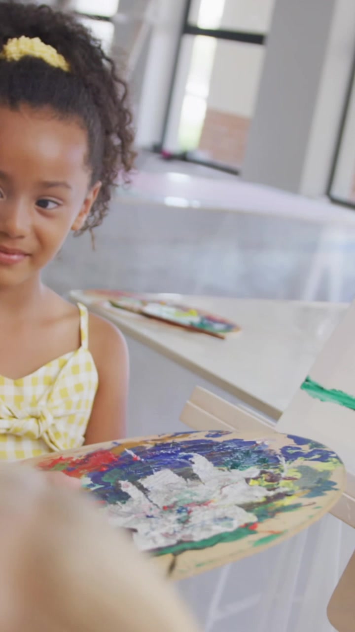 Animação de rastros de luz sobre crianças em idade escolar diversas pintando.