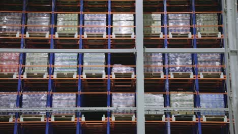 warehouse storage supply rack shelves with rows of boxes on pallets slow dolly right