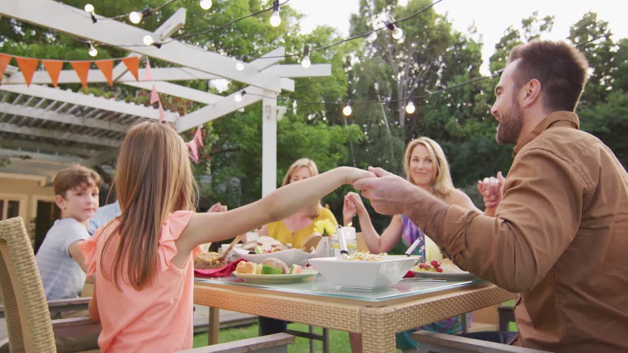 3 세대의 가족이 야외에서 점심을 먹기 전에 손을 잡고 있습니다.