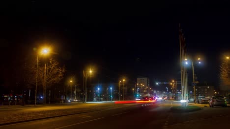 Zeitraffer-Des-Stadtverkehrs-Auf-Der-Straße-Von-Liepaja,-Ampelstreifen,-Straßenbahnschienen-Mit-Schnell-Fahrenden-Straßenbahnen,-Fußgänger,-Die-Auf-Die-öffentlichen-Verkehrsmittel-Warten,-Totale