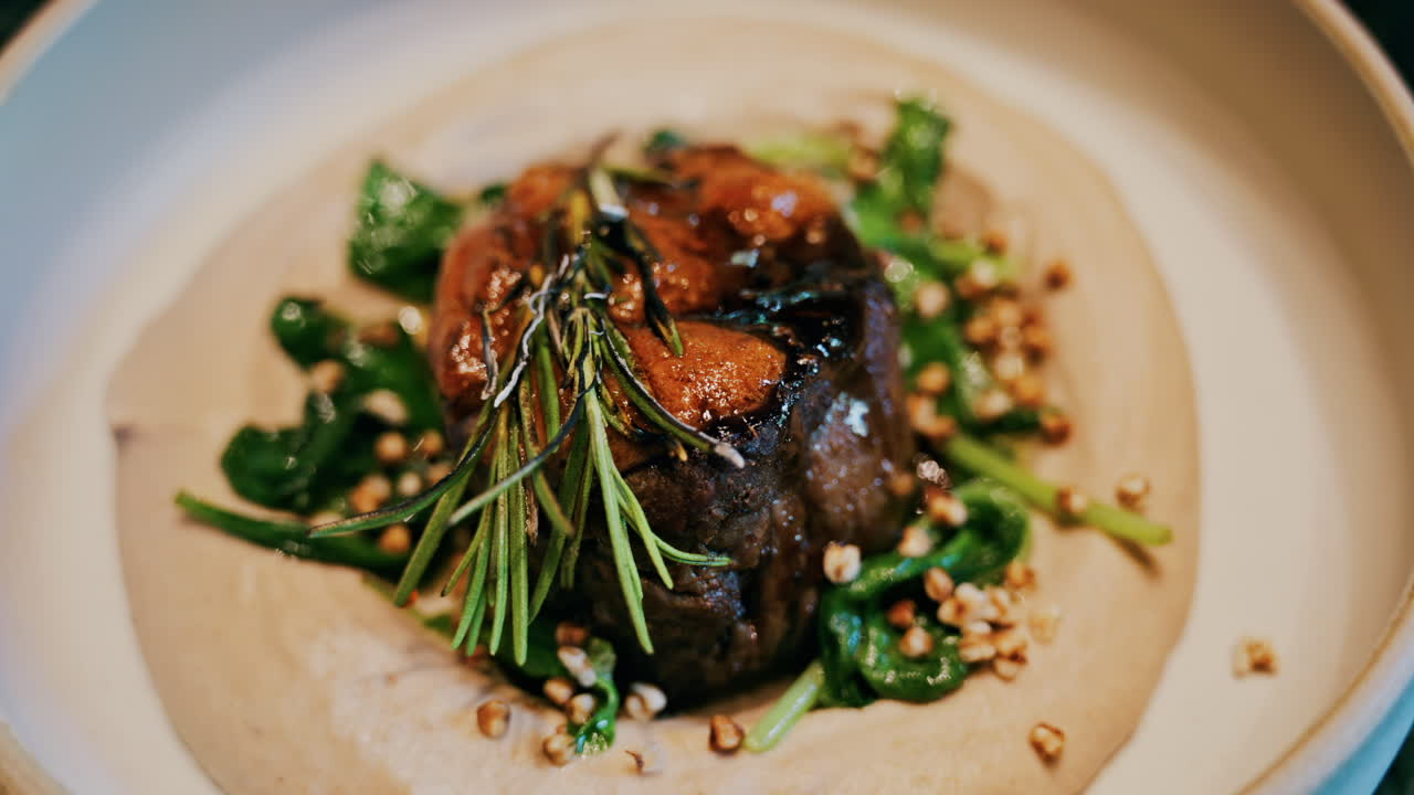 Close up of a beautifully plated beef filet, topped with a golden crust and garnished with rosemary