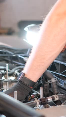 close-up of a mechanic working on a car engine with a flashlight