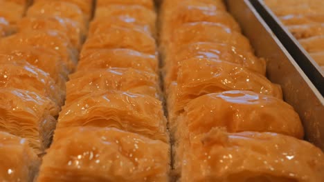 turkish baklava in metal baking trays on the display case. dolly shooting. the camera in motion shoots different types of baklava moving along the baking sheets. close-up. 4k