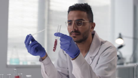 scientist conducting a lab experiment with test tubes and a pipette