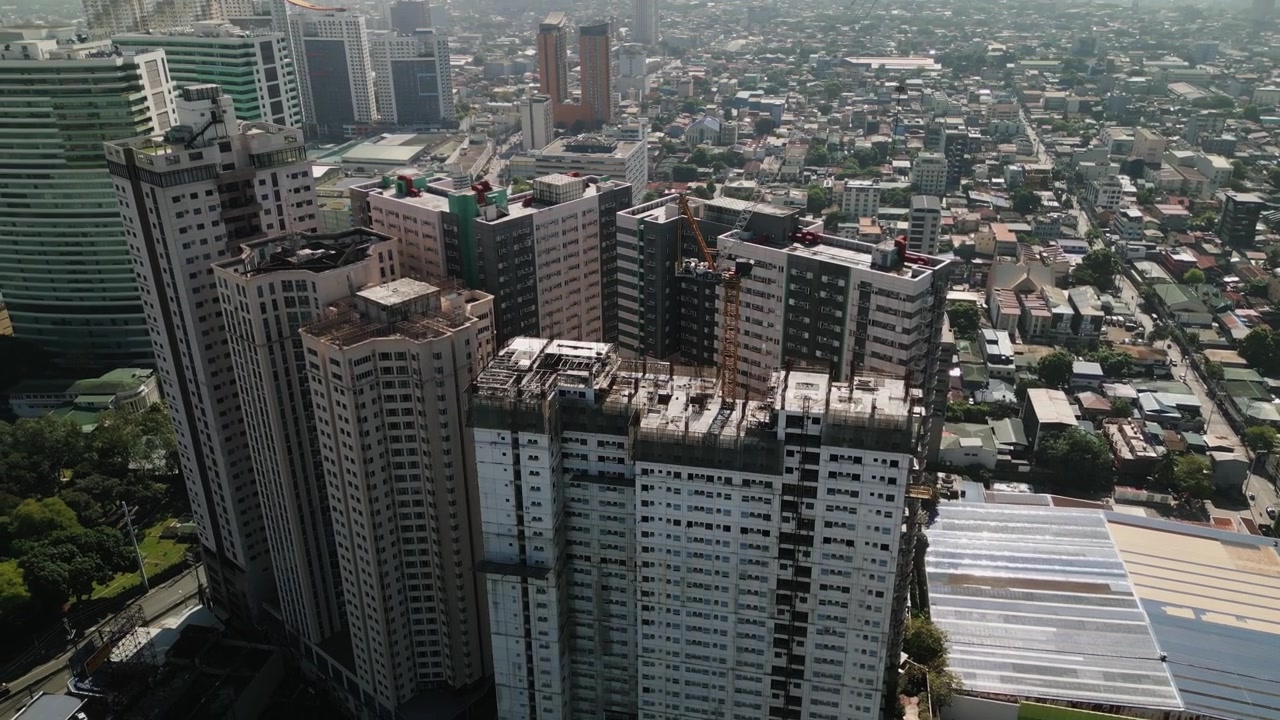 Órbita aérea de torres de condomínio em construção em Cubao, Metro Manila, cercadas por edifícios densos e desenvolvimento urbano - Filipinas