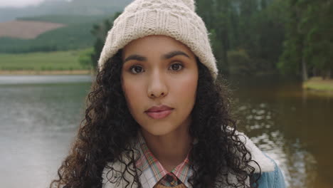 portrait beautiful mixed race woman looking serious expression wearing beanie for cold winter outdoors in nature by lake