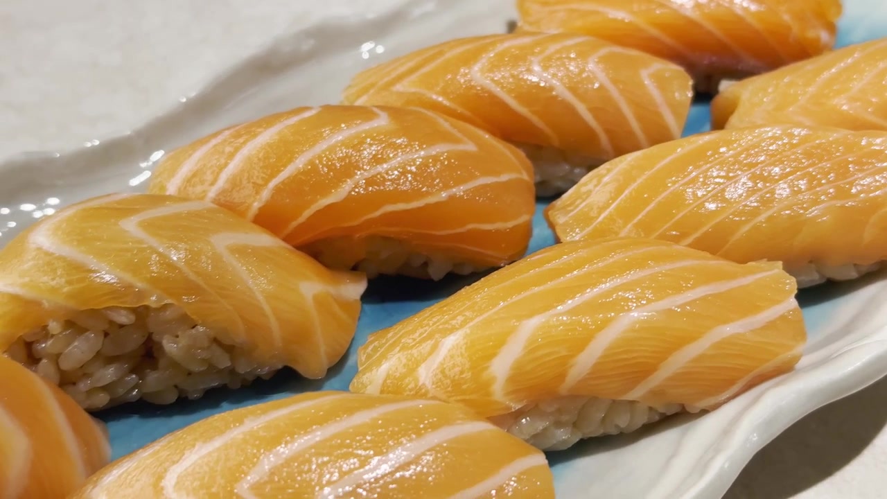 Primo piano di un generoso assortimento di sushi fresco al salmone disposto su un piatto da portata, che mostra colori vivaci, pesce pregiato e un'elegante presentazione giapponese.