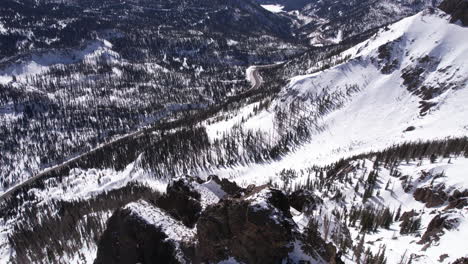 drone shot of snow capped hills and forest by mountain pass in countryside of colorado usa