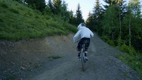 mountain biker performs a trick off a jump at sunrise