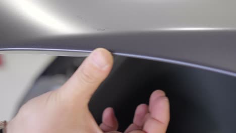 thumb pushes on paint protection film at edge of car's bonnet close up