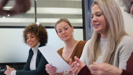 Line-Of-Businesswomen-Collaborating-In-Creative-Meeting-Studying-Documents-Around-Table-In-Office