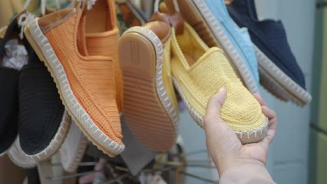 woman's hand holding a pair of yellow shoes in a shop