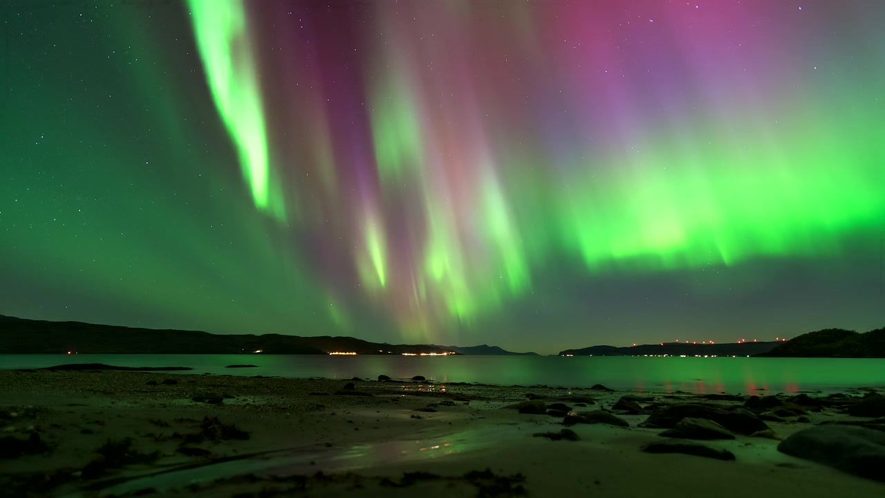 Timelapse: magiche luci polari, aurora boreale che danza nel cielo notturno sopra un fiordo