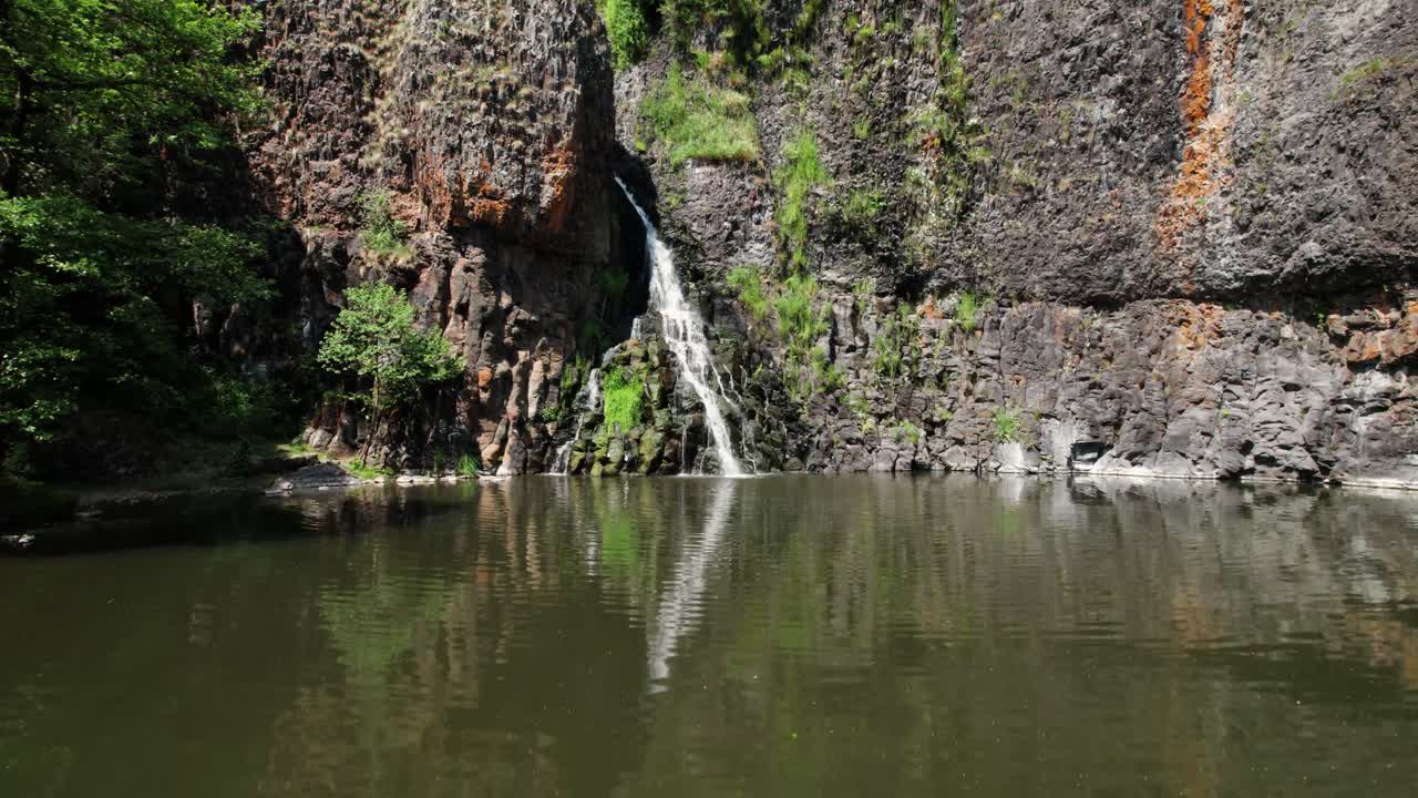 aerial shot over the Sailhant waterfall on a sunny day in Barbory village, Cantal department, Auvergne Rhone alpes region, France