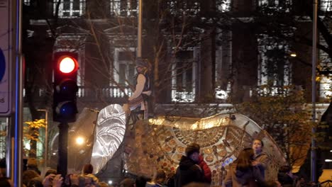 a close-up of a mechanical elephant float at the three kings parade (cabalgata de reyes) with a masked pirate-like figure, surrounded by festive crowds and historic buildings in the background.