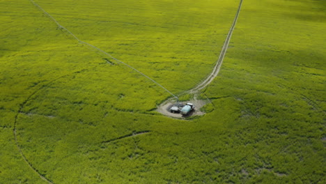 center pivot irrigation with tank truck in middle, green farm field, aerial