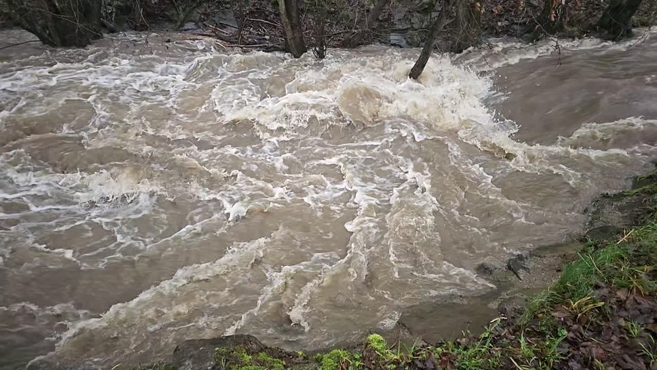 Dirty flood water flowing fast in the river, abstract close-up, super slow motion video