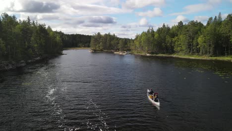 Aerial-view-of-drone-flying-over-Canoers-paddling-between-green-pine-forest-groves-on-a-Swedish-lake-in-Glaskogen-nature-reserve