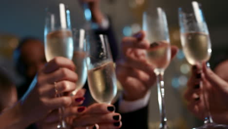 friends holding up champagne flutes together in a toast at party