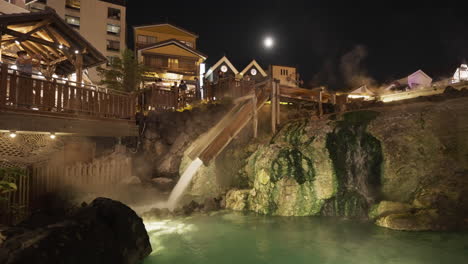 famoso yubatake en kusatsu, japón, durante la noche se ilumina con turistas en kimono de verano japonés tradicional tomando fotografías de la hermosa cascada de aguas termales