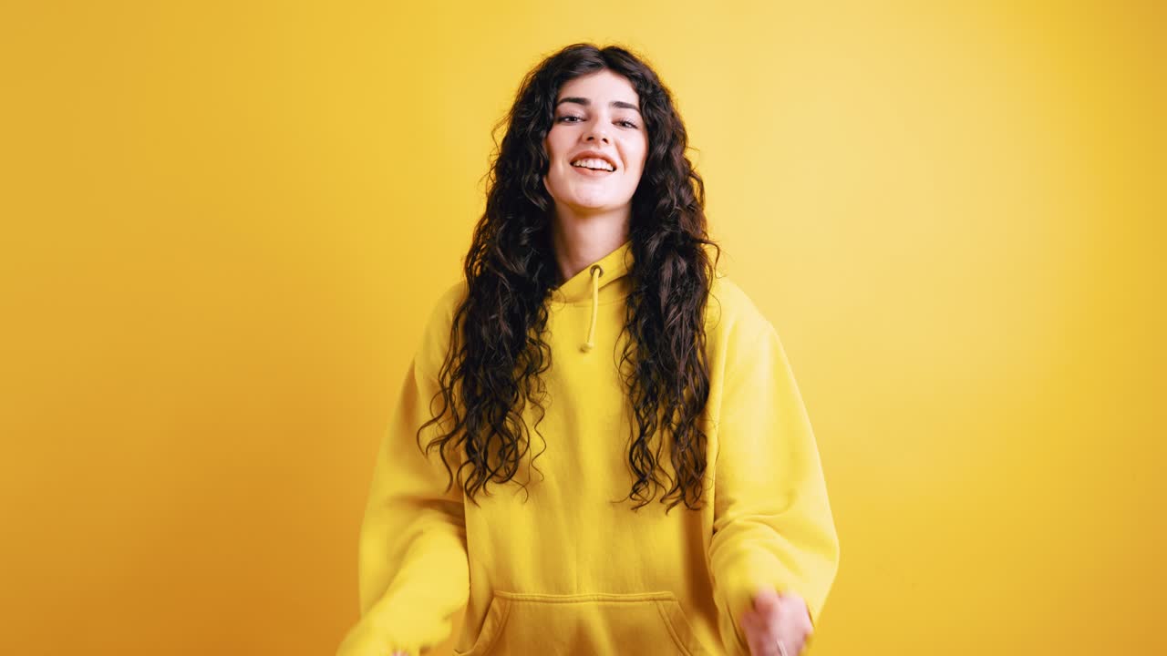 Happy woman with curly hair in yellow hoodie