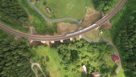 Overhead-drone-captures-lush-green-summer-scene:-train-gracefully-traversing-Semmering-viaduct,-blending-nature-with-engineering-marvel