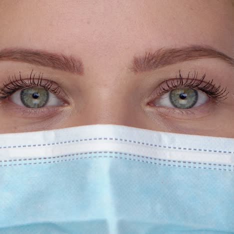 Young-woman-posing-in-medical-face-mask--Looking-at-camera-with-smile-behind