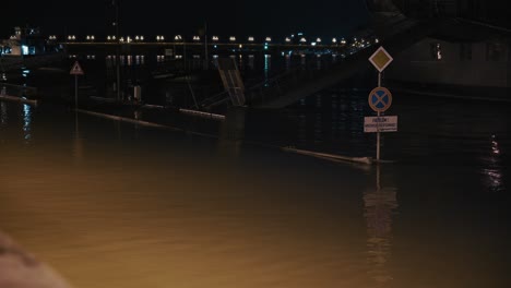 flooded street signs and walkway partially submerged at night during the budapest flood 2024