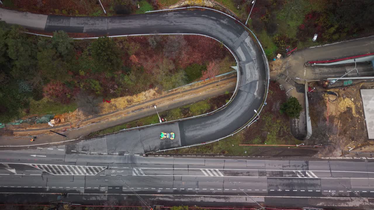 Veduta aerea di un'auto da rally che percorre una stretta curva a gomito vicino allo Stadio di Strahov a Praga durante l'autunno