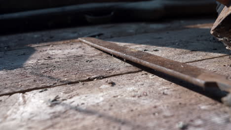 Old-rustic-tools-sit-on-wooden-workbench-in-afternoon-sunlight