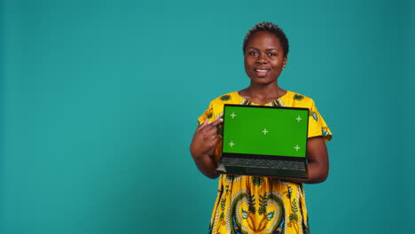 Young-adult-showing-a-laptop-with-isolated-mockup-screen-in-studio