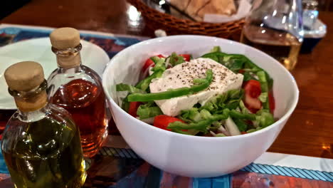 traditional greek salad in a bowl topped with feta cheese. zoom out shot