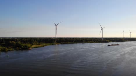 Antena-Sobre-Oude-Maas-Con-Turbinas-De-Viento-Inmóviles-Y-Silueta-De-Barco-Acercándose-En-La-Distancia