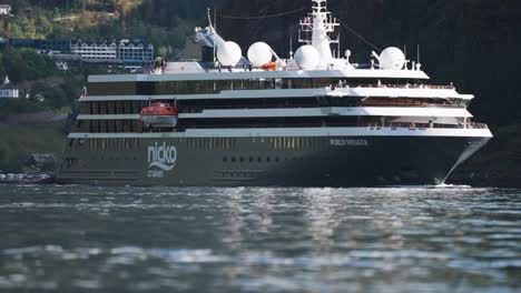 a large cruise liner leaves the port in the egeiranger fjord and moves slowly along the fjord.