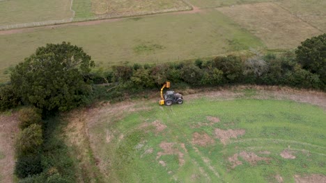 Aerial-Tracking-View-Of-Tractor-Cutting-And-Maintaining-Hedge-In-Field