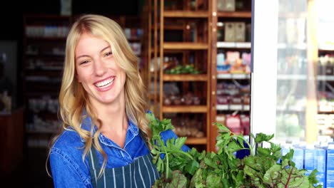 smiling staff holding a basket of fresh vegetables in organic section