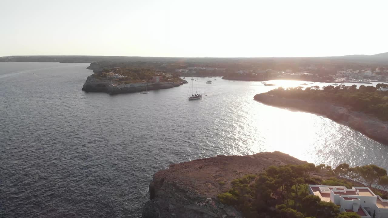 AEREA: Costa di Maiorca al tramonto e yacht a vela che esce dalla baia del porto