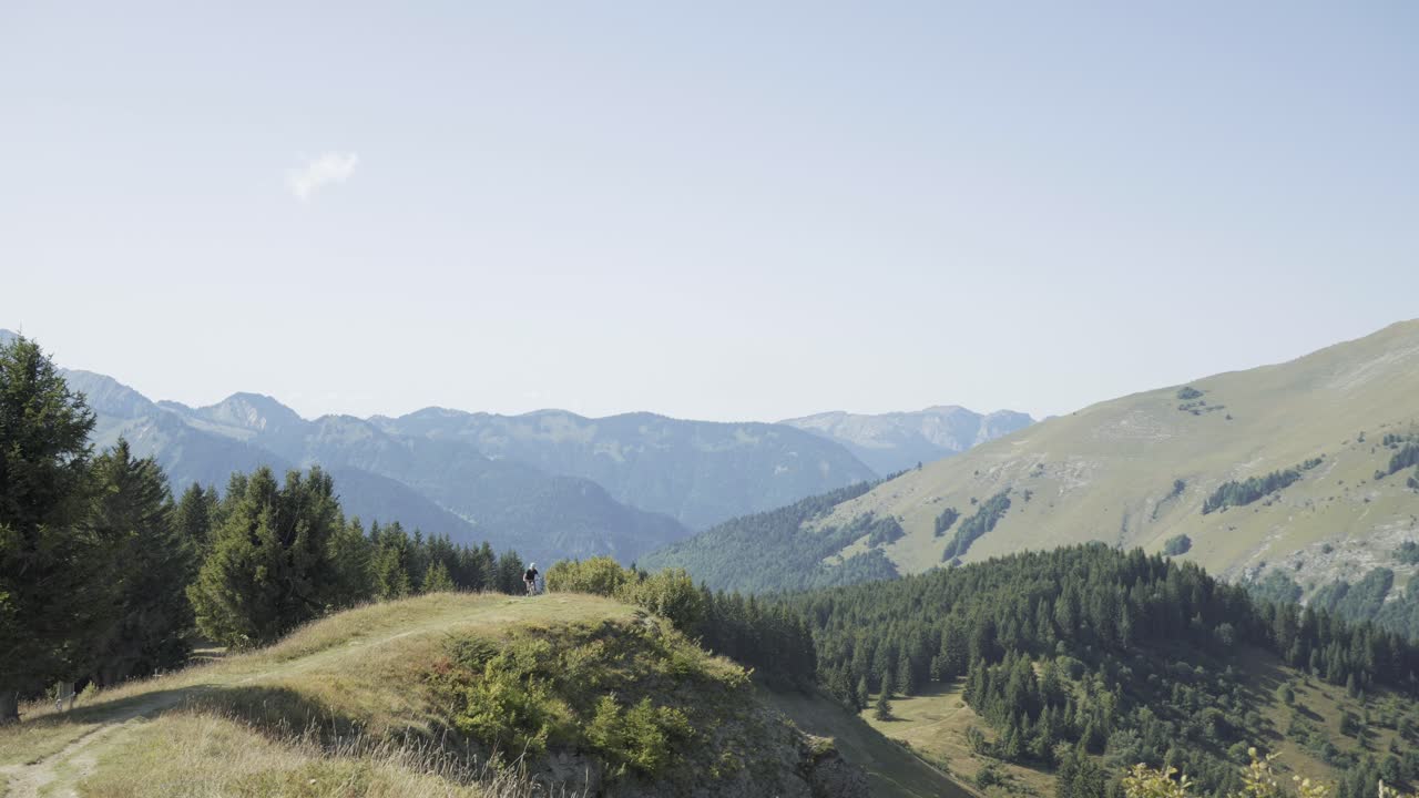 Mountainbiker, der træder op ad en naturskøn højderyg i Alperne.