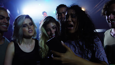 grupo de amigos revisando imágenes en el teléfono móvil en un concierto 4k