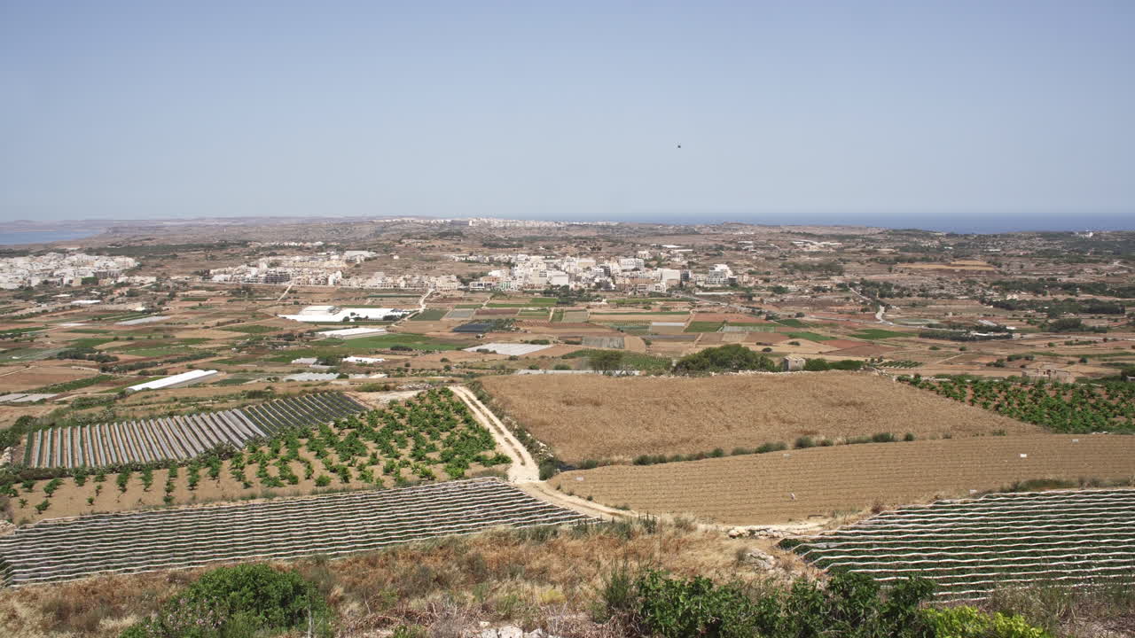paisaje rural de 4k con el mar mediterráneo y un pequeño pueblo a lo lejos en la isla de malta durante un caluroso día de verano