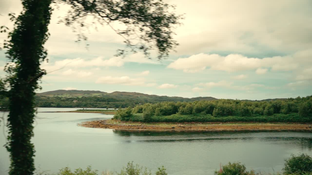 Driving through beautiful Irish countryside, lake and trees passing in slow motion on sunny summer day, 4k scenery