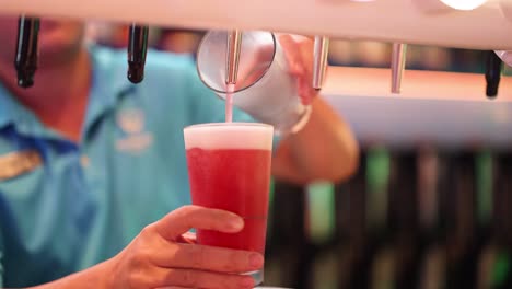 el camarero vertiendo cerveza roja en un vaso