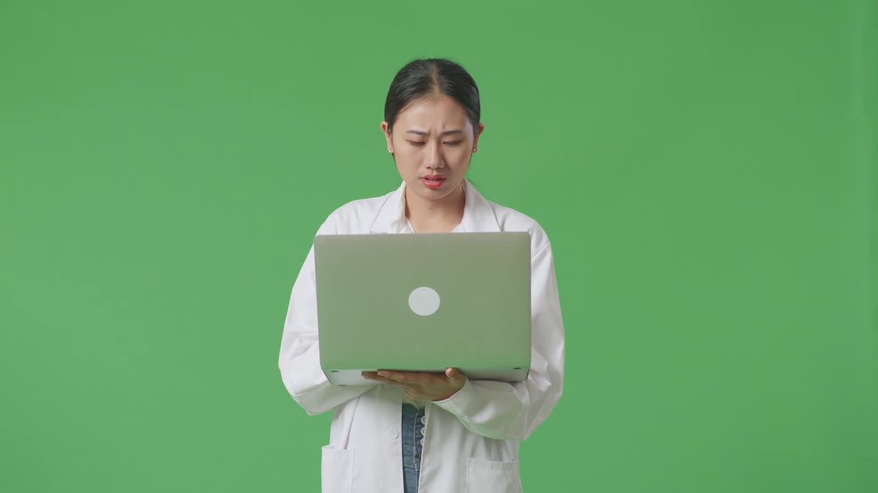 실험실 코트 를 입은 여자 가 노트북 을 보고 있다