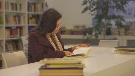 middle-aged woman reading a book in library. tilt-up