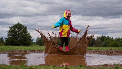 child happily jumping and splashing in a muddy puddle
